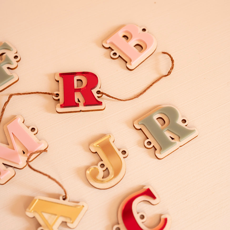 Plusieurs lettres en bois et relief plexi coloré (alternance miroir or, rouge, rose et vert)
Il y a un trou de chaque côté la découpe du lettrage, une cordelette y est pasée
