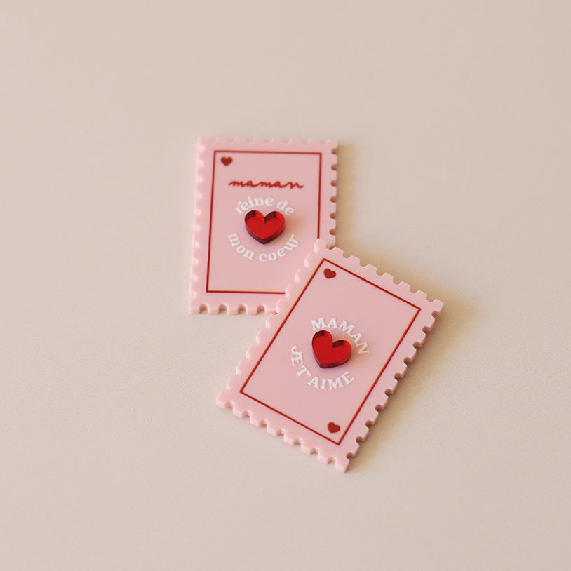 Magnet en plexi coloré rose et rouge, design de carte à jour, forme de timbre et coeur au centre en relief. Inscription maman je t’aime ou reine de mon coeur