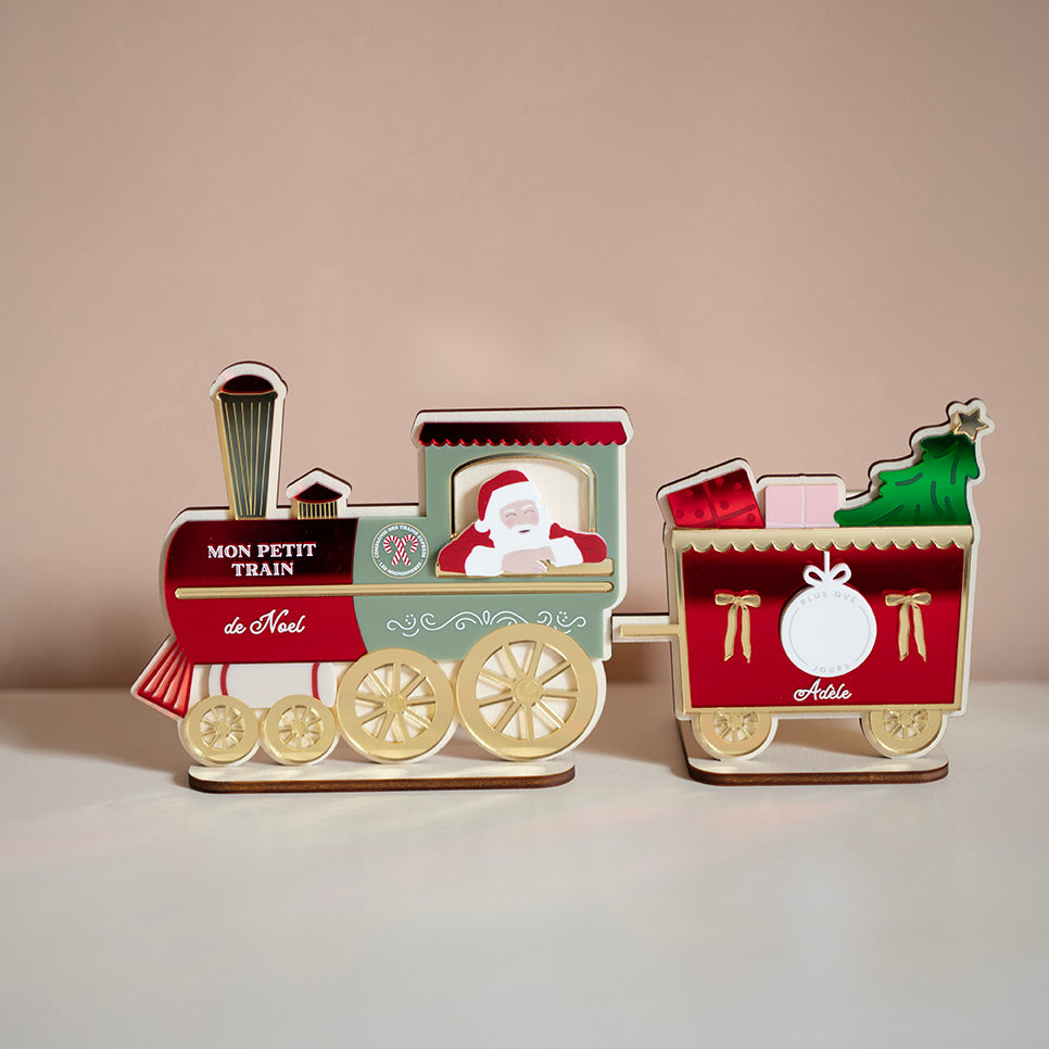 Décor en bois avec relief coloré 
Représentation d’un petit train 
Locomotive rouge, verte et doré avec père-noël accoudé à la fenêtre. Sur le devant il est inscrit « Mon petit train de Noël »
Derrière 1 wagons constitué d’un fond rouge avec détail doré, deux cadeaux et un sapin sorte du dessus. Au centre un rond blanc, sur le coté 2 noeus dorés. Il est inscript le prénom « Adèle »